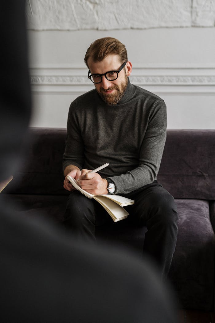 Male professional in a cozy office setting taking notes during a session or meeting.